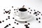 White cup of coffee on a white saucer on a white background isolate, close-up, top view, coffee beans lie