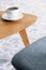 White cup of coffee on wooden table in minimal grey living room interior. Real photo