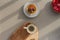 A white cup of espresso with milk on a wooden background and cakes with nuts and strawberries on a gray background.