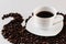 White cup with freshly poured coffee Close-up with a saucer and coffee beans around on a white background.