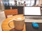 A white cup hot capuccino with white heart mug on top, a white screen computer labtop and blue mouse on brown wooden table