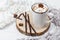 White cup of hot cocoa with marshmallows and chocolate sticks on wooden stand