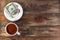 White cup with invigorating espresso coffee and saucer with two American dollar bill and coin. On dark wooden background. Payment