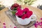 White cup with pink roses and green bowl with strawberries lying on stylish wooden board.