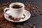 White Cup of strong coffee in roasted coffee beans, on a solid black background, foreground, close-up