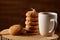 White cup of tea and bunch of cookies on a log over country style wooden background, close-up, selective focus