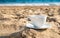 White cup with tea or coffee on sand beach front of sea