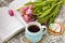 White cup of tea in a knitted blue case with an open book and with pink flowers tulips and sweets, with gingerbread on a textural