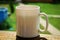 A white cup of tea on the railing of the Wooden terrace. Morning concept. Close-up