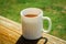 A white cup of tea on the railing of the Wooden terrace. Morning concept. Close-up