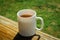 A white cup of tea on the railing of the Wooden terrace. Morning concept. Close-up