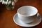 White cup for tea on a white saucer on a wooden table and a bouquet of snowdrops