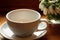 White cup for tea on a white saucer on a wooden table and a bouquet of snowdrops