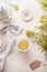 White cup of yellow herbal tea on light table with tea pot and fresh herbs and flowers. Organic Tutsan tea. Wild medicinal plant