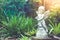 White cupid sculpture or statue standing in outdoor garden surrounded with green natural.