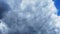 White and dark clouds fly rapidly across the blue sky. Time lapse atmosphere. Weather changes. Movement of clouds across