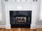 A white detailed ornate wood mantle with a gas fireplace in a new construction house