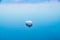 White dinghy afloat on calm blue water with reflection of sunset colors