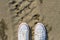 White dirty sneakers with a red stripe on a sandy summer background.