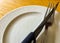 White dish with folk and knife on the wooden table