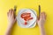 White dish with ketchup shaped, hands with knife and fork