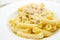 White dish with penne and carbonara sauce
