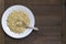 White dish with sprouted buckwheat and spoon inside on wooden table