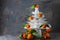White dishes Pyramid like Christmas tree with mandarins with leaves on top, bunch below on dark Creative concept