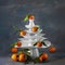 White dishes Pyramid like Christmas tree with mandarins with leaves on top, bunch below on dark Creative concept, dishware, veg,