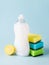 White dishwashing liquid in a plastic bottle, lemon and three foam sponges. Purity and household chemicals. Kitchen detergent on a