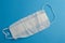 white disposable mask on a blue matte background. a gauze mask to protect the respiratory system from infections. personal