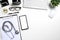 White doctors desk with stethoscope, blank screen smart phone, pen, keyboard and cup of coffee.Top view with copy space