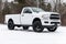 White Dodge Ram truck parked on a concrete surface in a natural setting.