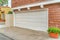 White door of two car garage of home with shingle cladding on the exterior wall