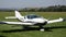 White double-seat propeller-driven PS-28 Cruiser airplane stops moving on grass landing strip in