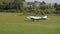 White double-seat propeller-driven PS-28 Cruiser airplane takes off on grass landing strip in co