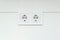 White double socket on wall. Electrical plug into a wall socket. European electrical outlet on white wall background