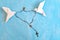 White dove origami carrying rosary or scapular in sky blue background.