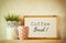 White drawing board with the phrase coffee break over wooden table with coffe cup and flower pot decoration . filtered image