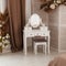 White dressing table with oval mirror and chair is part of cosy interior of beautiful bedroom