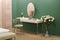 White dressing table with wicker elements, a room with a green wall and golden brass furniture, luxury mirror, female boudoir