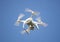 White drone with digital camera, filming from above. Clear blue sky background.