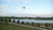White drone quadcopter flying in the blue sky over the river