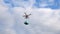 White drone in sky flies down and sideward with delivering gift box