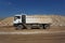 A white dump truck, lorry full of stones in a sand quarry, transporting of materials on a natural background.