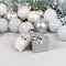 White Dzungarian hamster on a gift box. Christmas card with white and silver balls, garland, tinsel, snowflakes on a