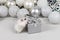 White Dzungarian hamster on a gift box. Christmas card with white and silver balls, garland, tinsel, snowflakes on a