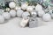 White Dzungarian hamster on a gift box. Christmas card with white and silver balls, garland, tinsel, snowflakes on a