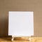 White easel with blank canvas on wooden desk