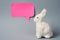 White Easter bunny with pink sticky note on gray background decoration animal Copy Space